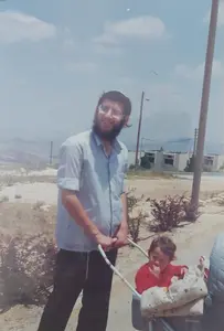 יגאל מטייל עם בתו ברוריה ובעגלה יהודה בן החודשיים ליד הכיכר שעדיין לא קיימת ביצהר קיץ תשמ''ט